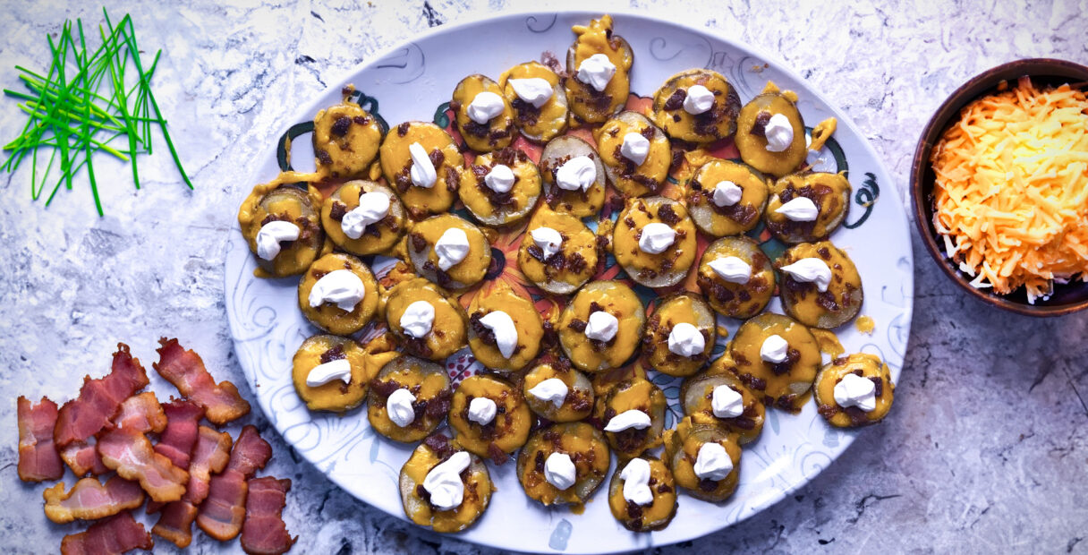 Loaded Baked Potato Bites on a counter with bacon and cheese on the sides